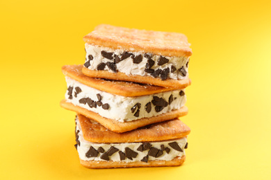 Photo of Sweet delicious ice cream cookie sandwiches on yellow background, closeup