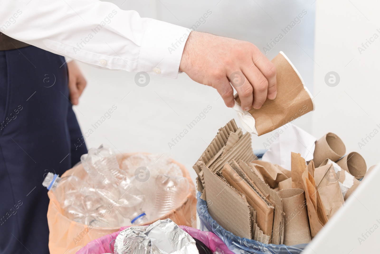 Photo of Man putting used paper cup into trash bin, closeup. Waste recycling