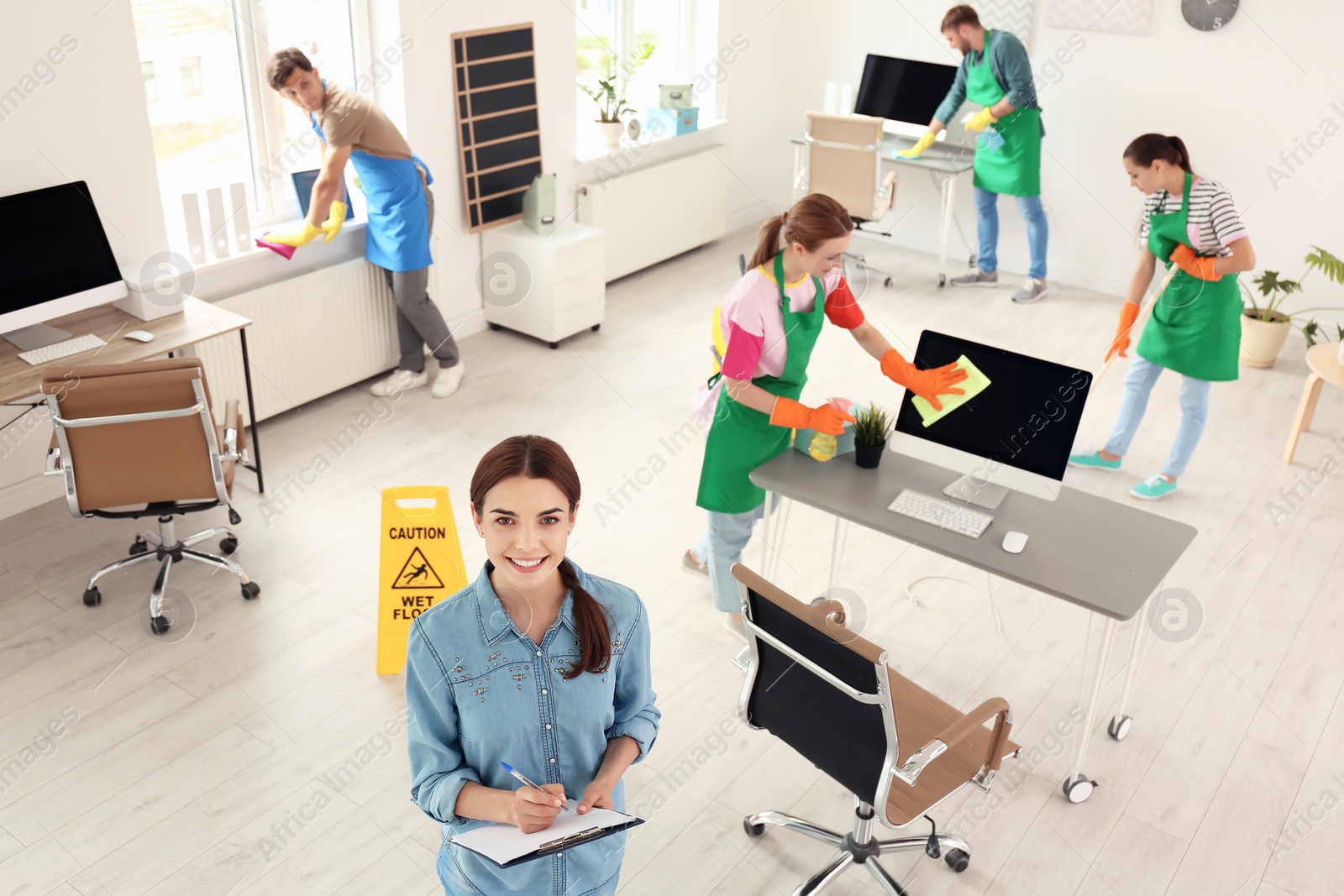 Photo of Team of professional janitors in uniform cleaning office