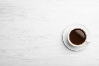 Ceramic cup with hot aromatic coffee on wooden background, top view