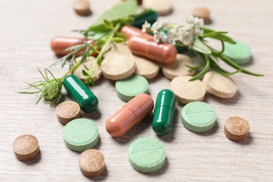 Photo of Different pills and herbs on wooden table, closeup. Dietary supplements