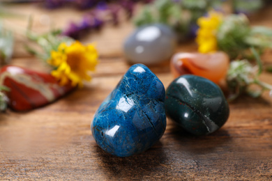 Photo of Different gemstones and healing herbs on wooden table, closeup
