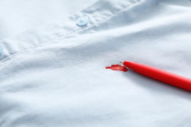Photo of Pen and stain of red ink on light shirt, closeup. Space for text