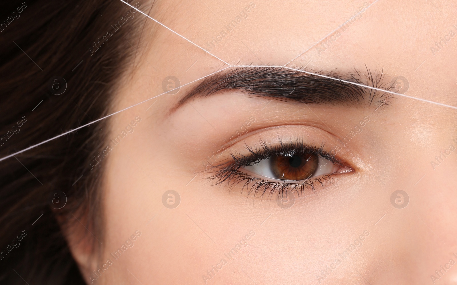 Photo of Young woman having professional eyebrow correction procedure, closeup