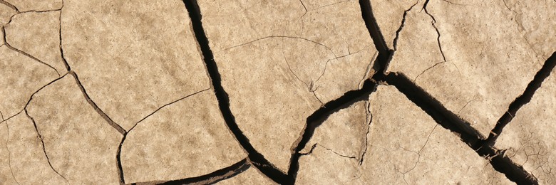 Dry cracked ground as background, top view. Banner design