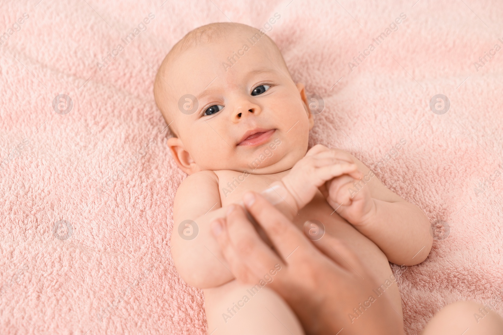 Photo of Woman applying body cream onto baby`s skin on bed, top view