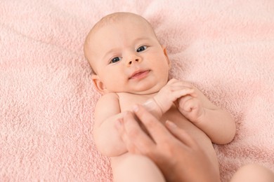 Photo of Woman applying body cream onto baby`s skin on bed, top view