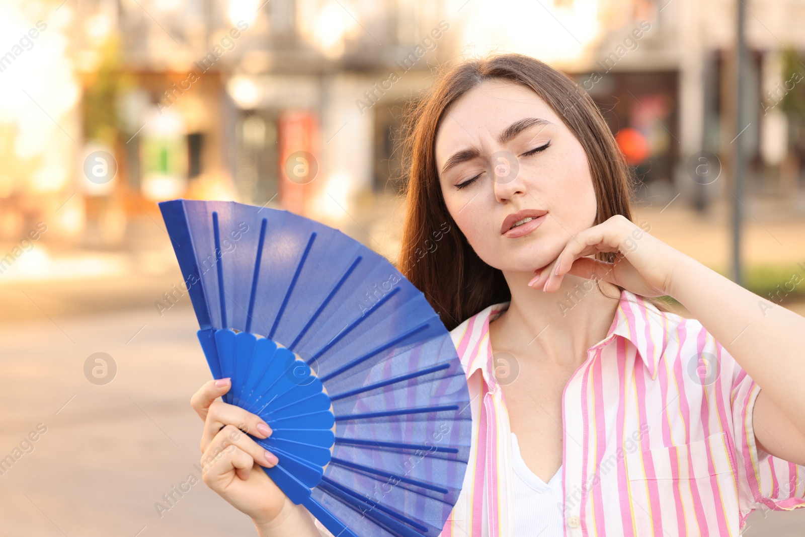 Photo of Woman with hand fan suffering from heat outdoors