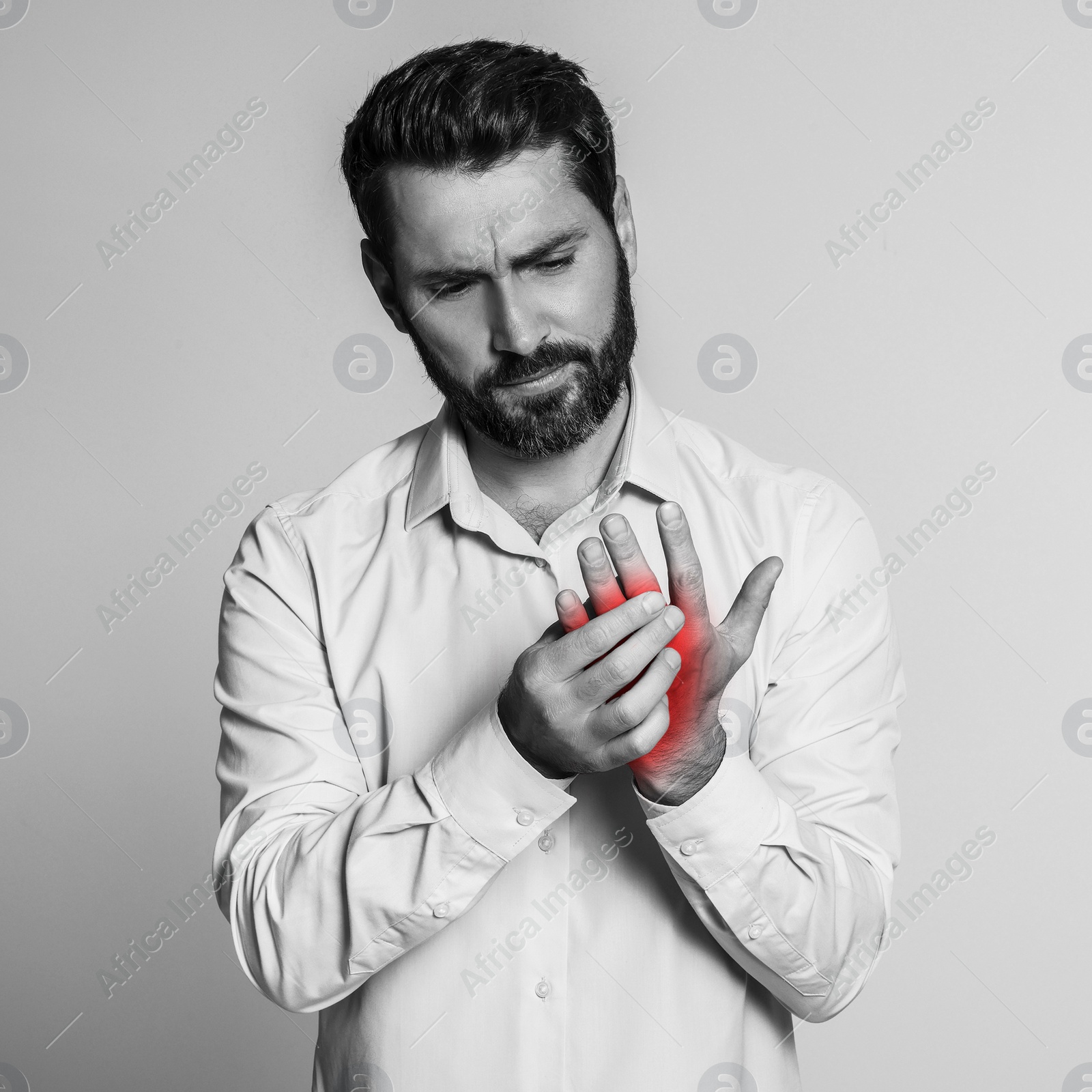 Image of Man suffering from rheumatism on light background. Black and white effect with red accent in painful area