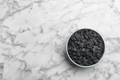 Bowl with raisins and space for text on marble background, top view. Dried fruit as healthy snack