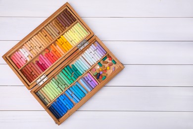Photo of Set of soft pastels in box on white wooden table, top view with space for text. Drawing material