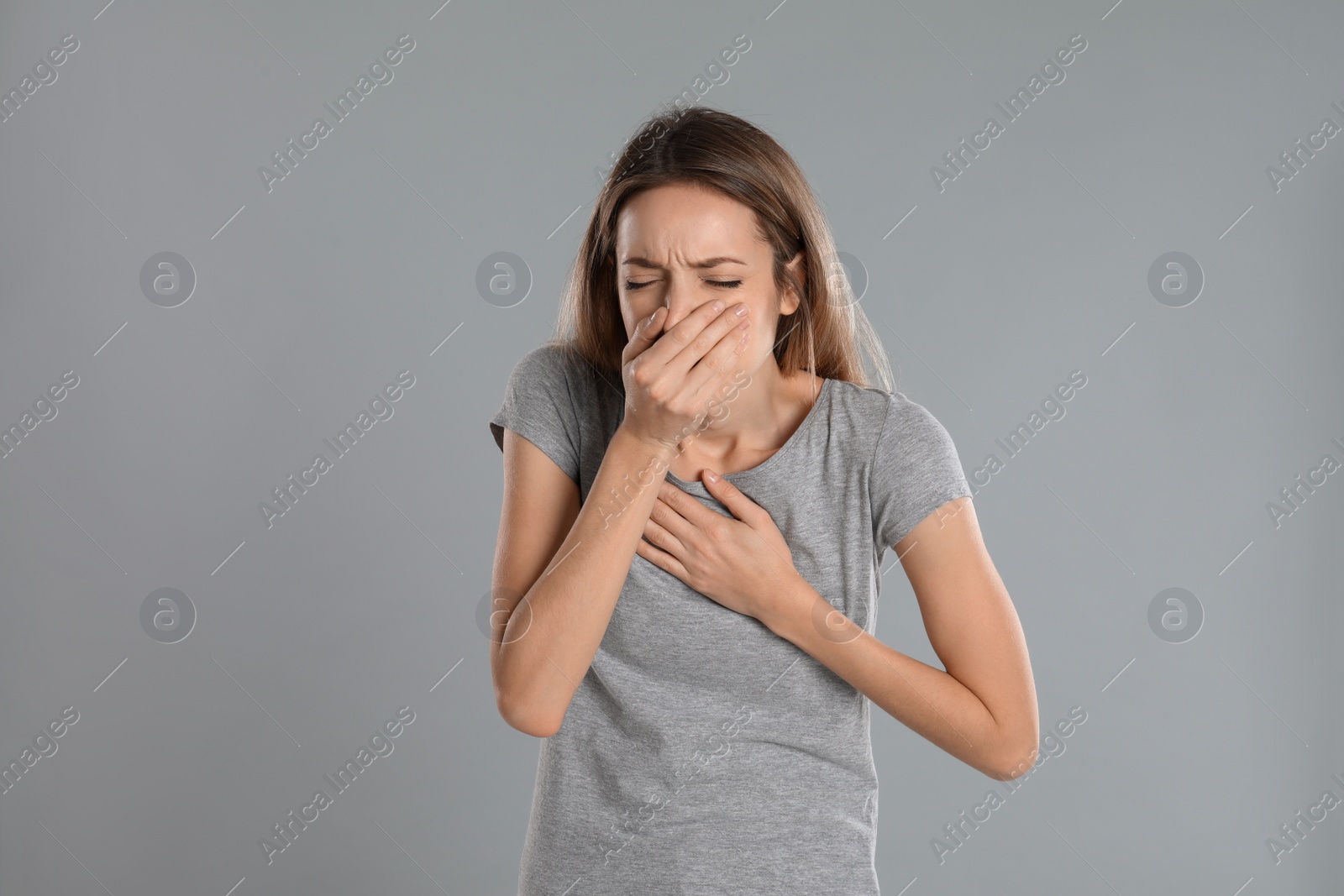 Photo of Woman suffering from nausea on grey background. Food poisoning
