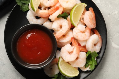 Tasty boiled shrimps with cocktail sauce, parsley and lime on light grey table, top view