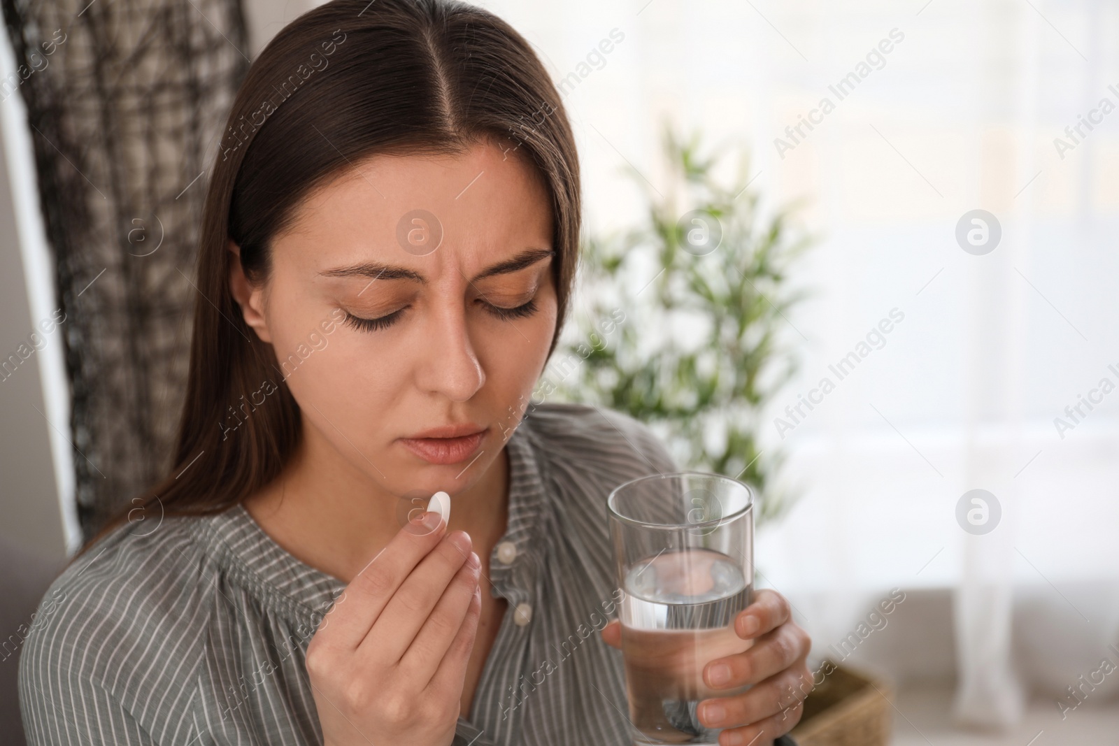 Photo of Sad young woman taking abortion pill at home