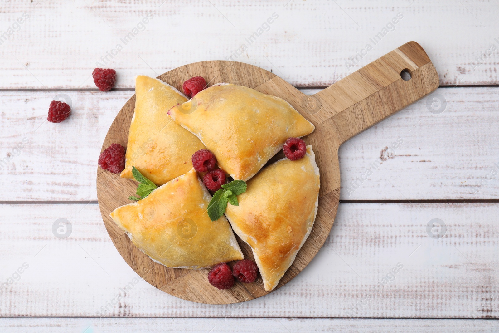 Photo of Delicious samosas with raspberries on white wooden table, flat lay