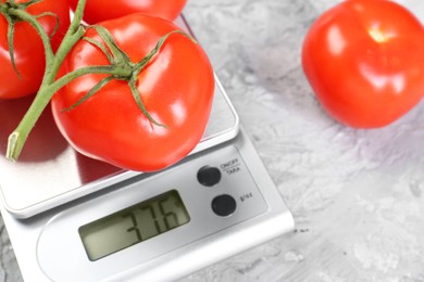 Photo of Kitchen scale with tomatoes on grey textured table, closeup