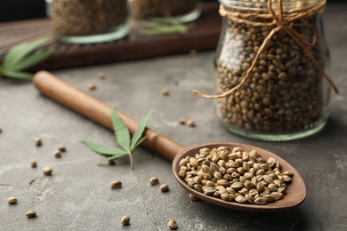 Photo of Organic hemp seeds in spoon on grey table