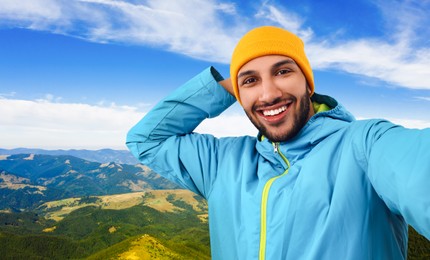 Image of Smiling young man taking selfie in mountains