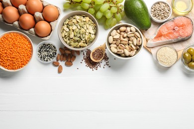 Photo of Different products high in natural fats on white wooden table, flat lay. Space for text