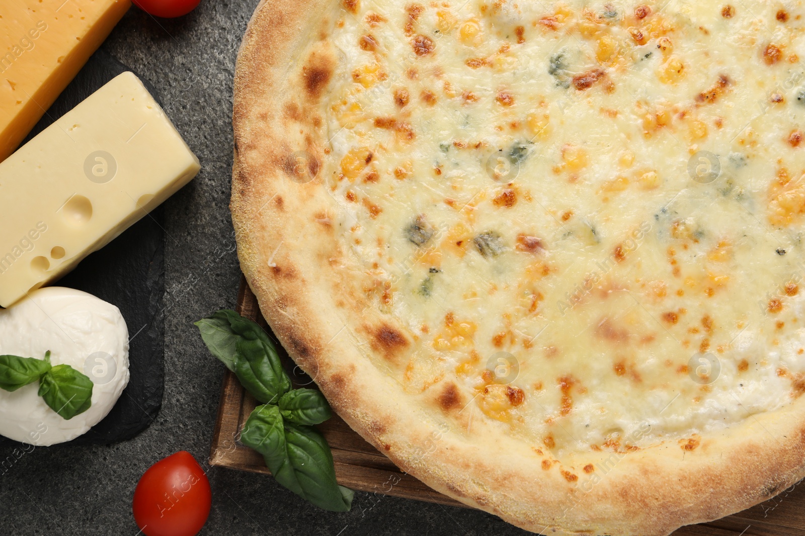 Photo of Delicious cheese pizza and ingredients on dark grey table, flat lay