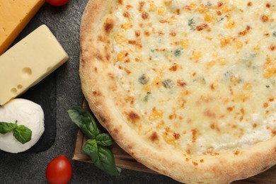 Photo of Delicious cheese pizza and ingredients on dark grey table, flat lay