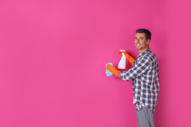 Man in gloves cleaning color wall with rag