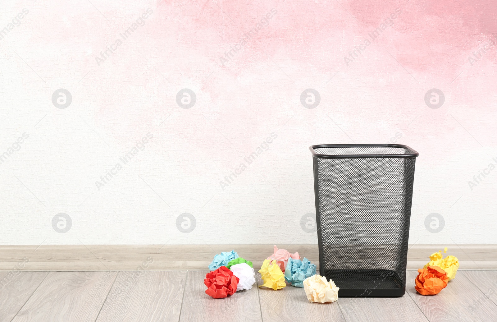 Photo of Basket with crumpled paper balls near pink wall. Space for text