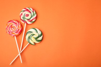 Photo of Colorful lollipops on orange background, flat lay. Space for text