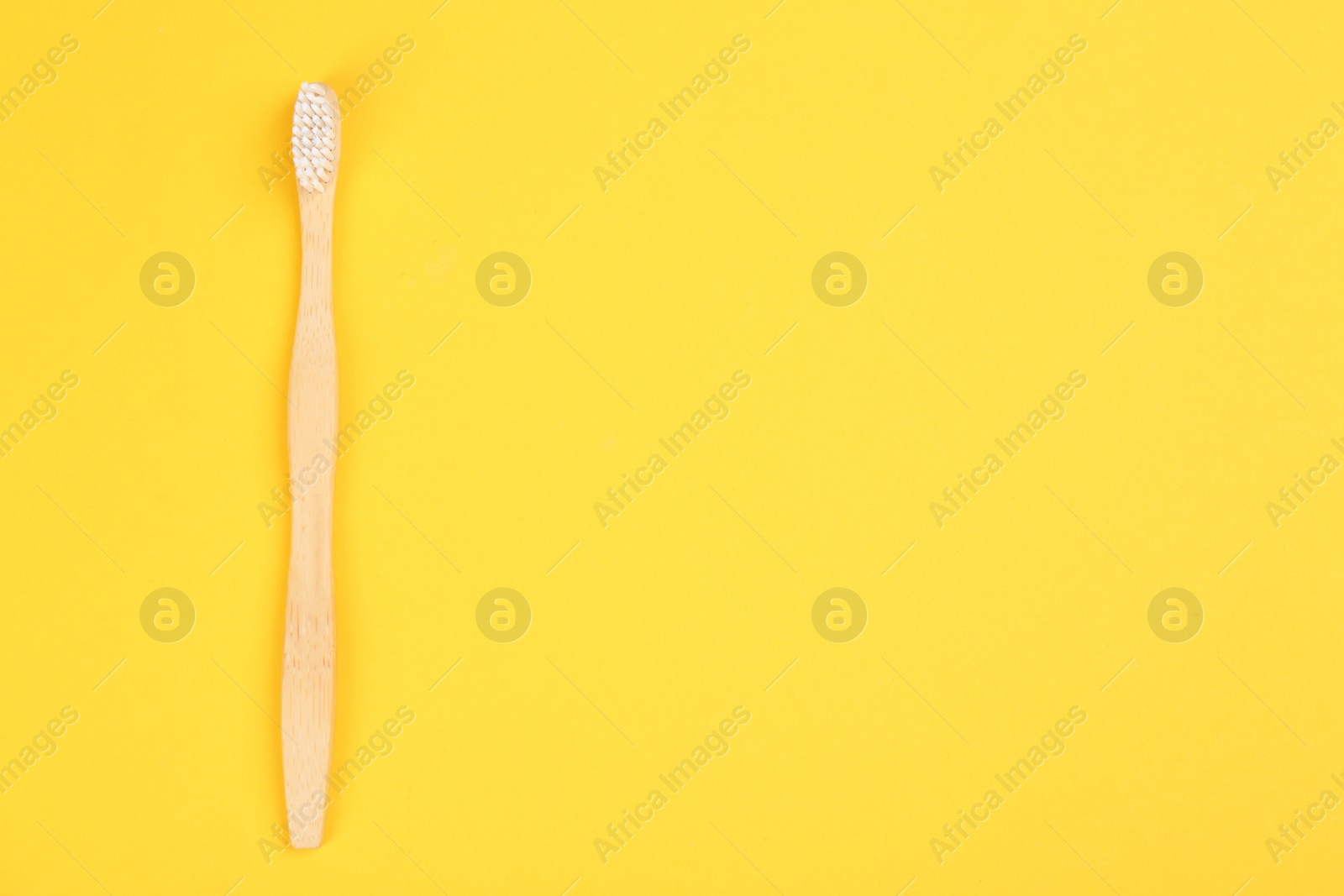 Photo of Toothbrush made of bamboo on yellow background, top view. Space for text