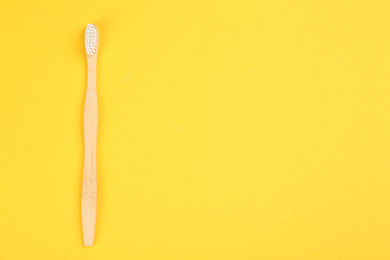 Photo of Toothbrush made of bamboo on yellow background, top view. Space for text