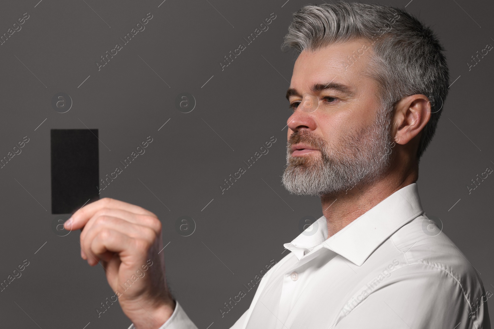 Photo of Handsome man holding blank business card on grey background