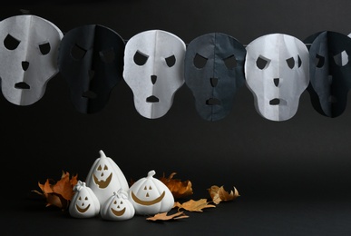 Photo of Jack-o-Lantern candle holders and fallen leaves on black background. Halloween decor