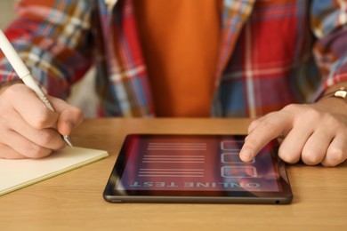Man taking online test on tablet at desk, closeup