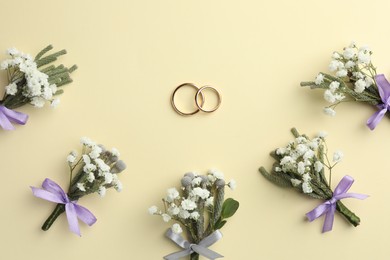 Photo of Small stylish boutonnieres and rings on beige background, flat lay