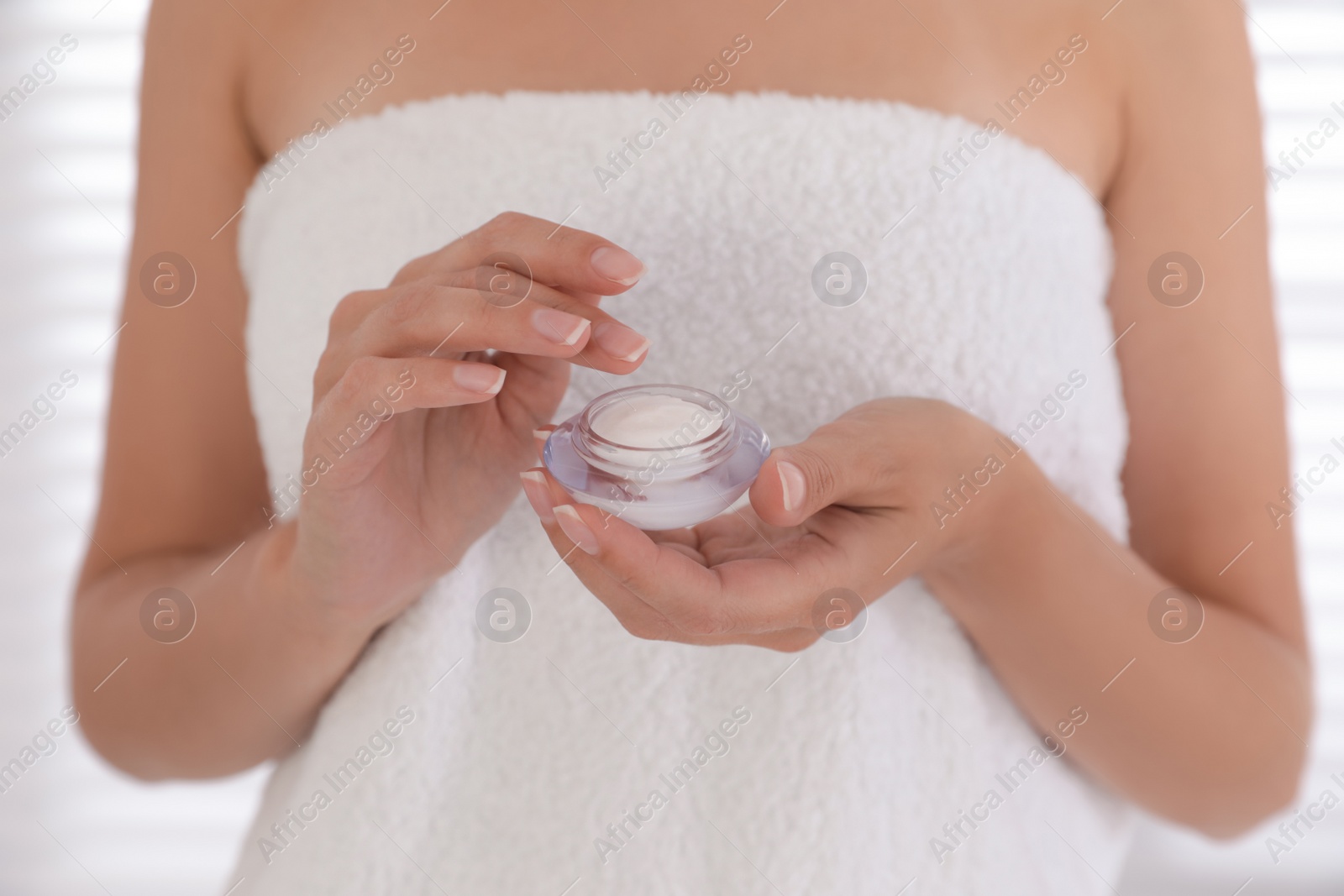 Photo of Woman holding jar with cream on light background, closeup