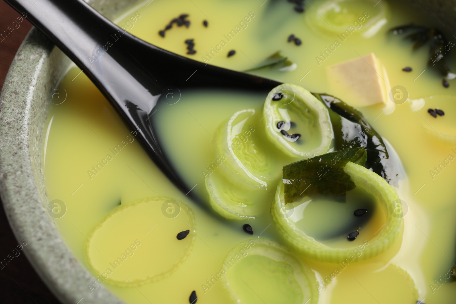 Photo of Bowl of delicious miso soup with tofu and spoon, closeup