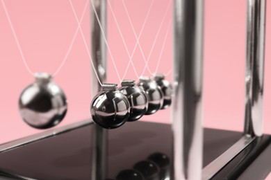 Newton's cradle on pink background, closeup. Physics law of energy conservation