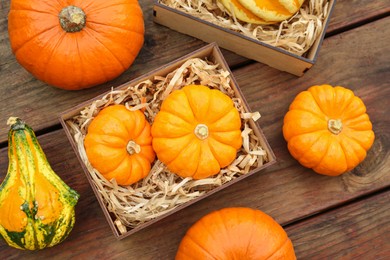Crate and many different pumpkins on wooden table, flat lay