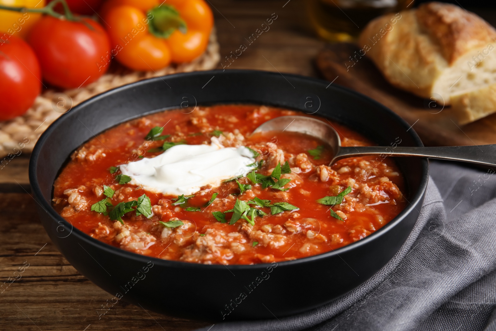 Photo of Bowl of delicious stuffed pepper soup on wooden table, closeup