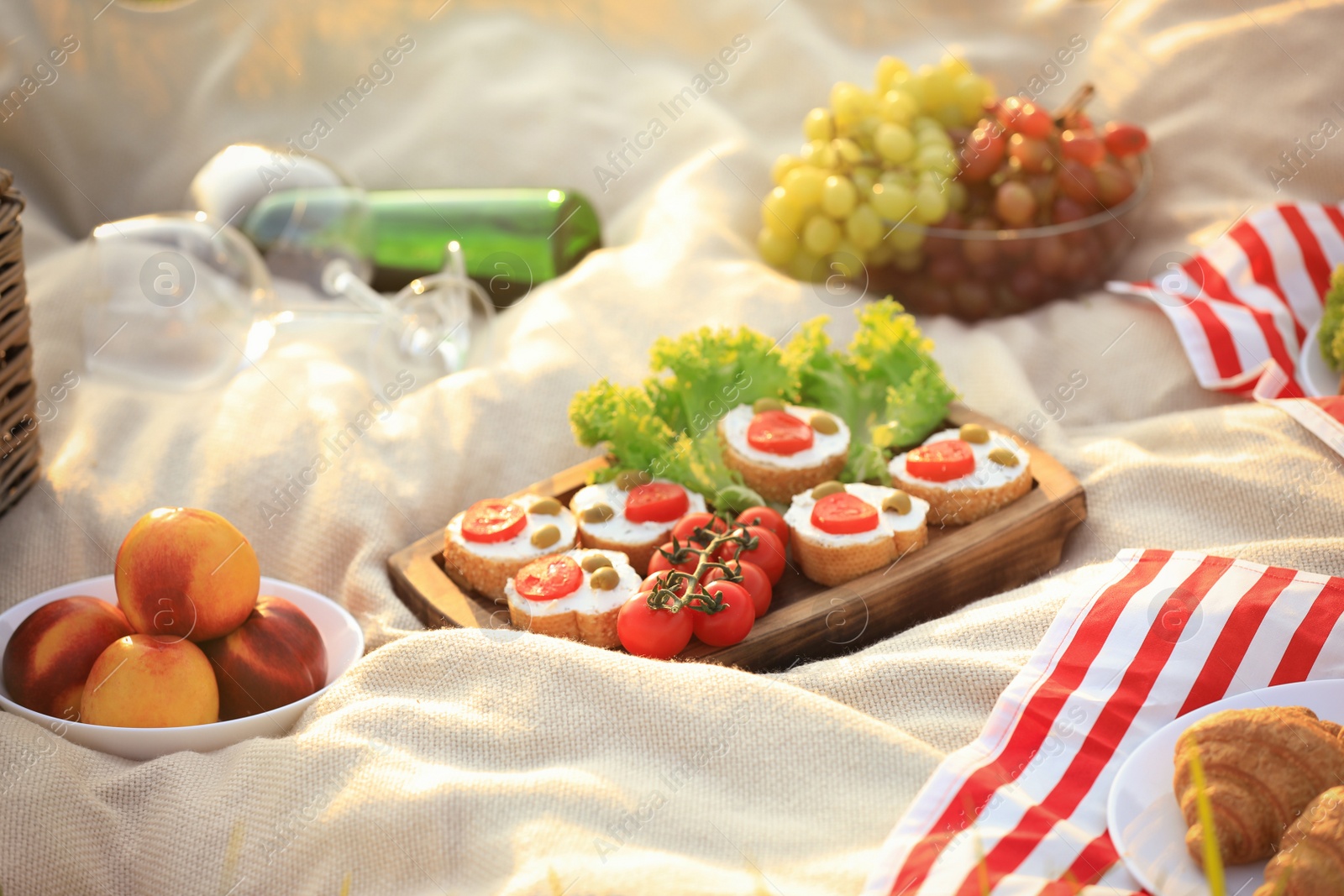 Photo of Picnic blanket with different snacks and wine outdoors