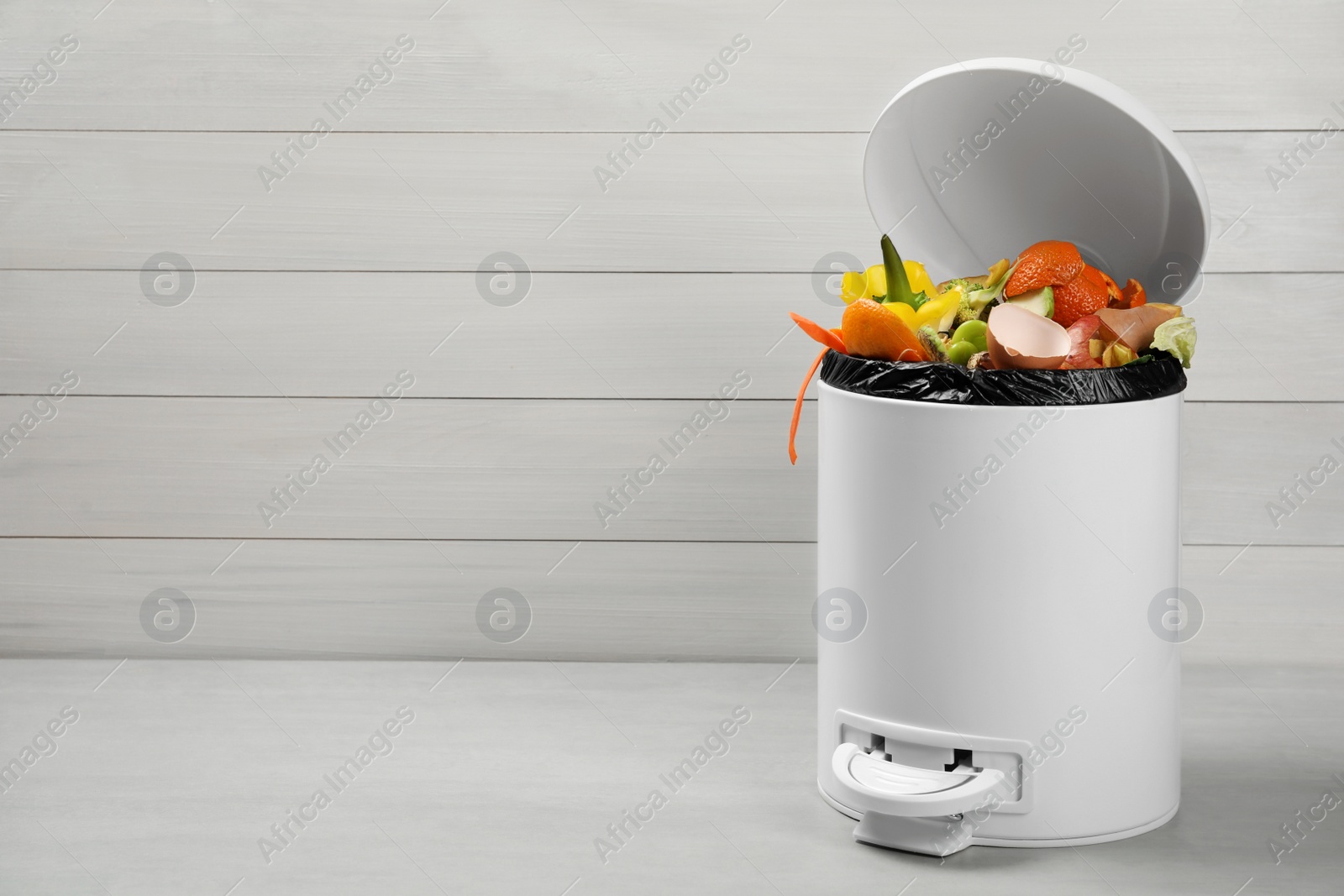 Photo of Trash bin with natural garbage on light background, space for text. Composting of organic waste