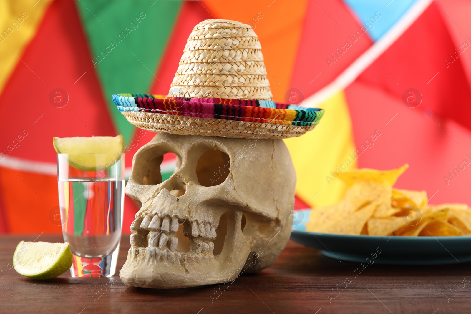 Photo of Human scull with Mexican sombrero hat and tequila on wooden table
