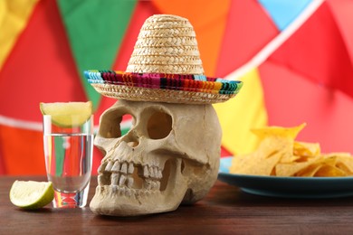 Human scull with Mexican sombrero hat and tequila on wooden table