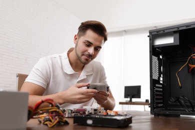 Male technician repairing computer at table indoors