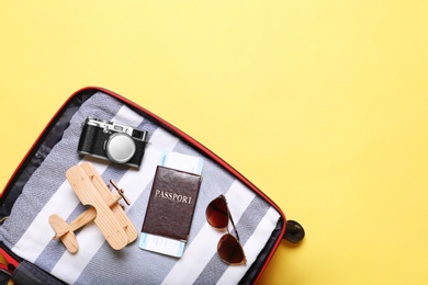 Photo of Open suitcase with beach objects on yellow background, top view. Space for text