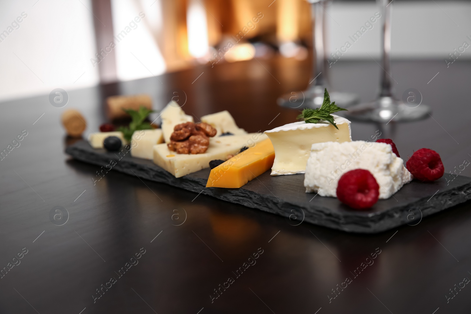 Photo of Different types of delicious cheeses with berries and nuts on table