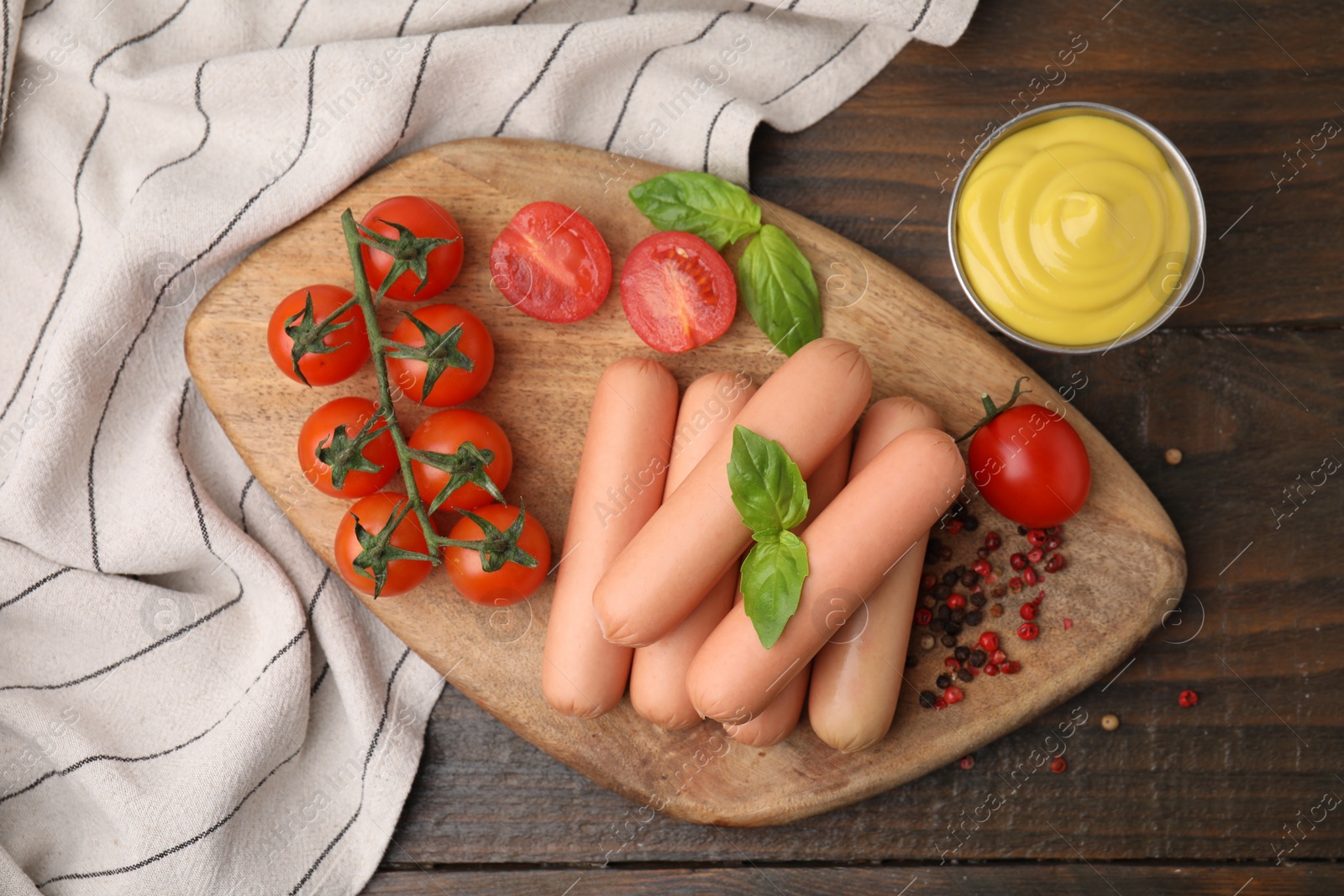 Photo of Delicious boiled sausages, sauce, tomatoes and spices on wooden table, flat lay