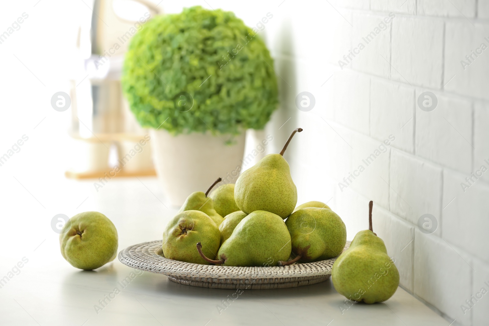 Photo of Fresh ripe pears on white countertop in kitchen