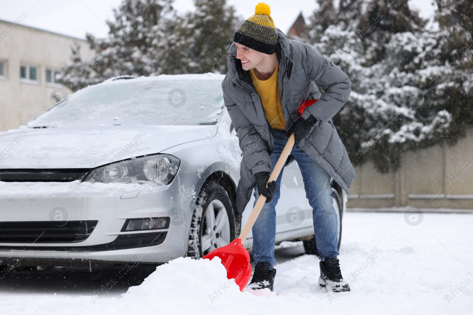 Photo of Man removing snow with shovel near car outdoors