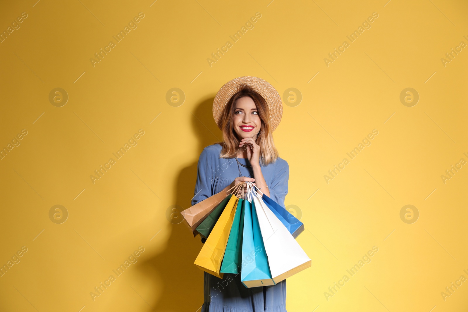 Photo of Beautiful young woman with shopping bags on color background